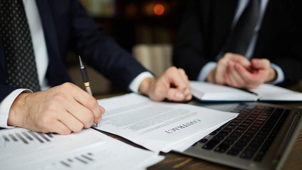 Business professionals review and discuss a contract document during a meeting.