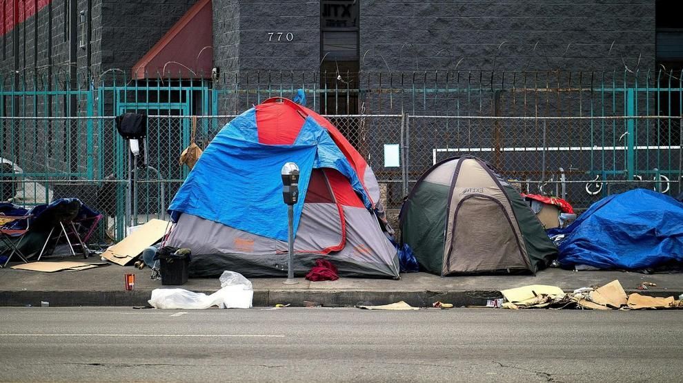 Tents line a sidewalk in Los Angeles with belongings and debris nearby.