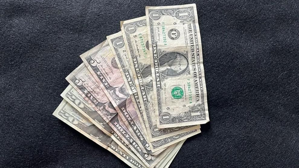 A collection of U.S. bills is displayed on a dark surface. Photo: Alan Wooten / The Center Square