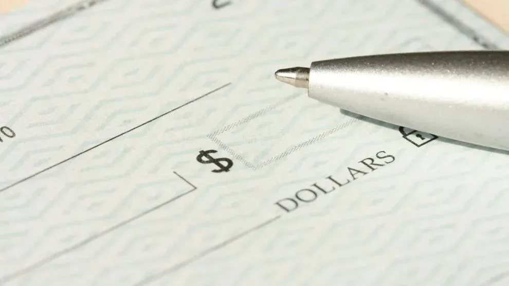 A close-up view of a blank check with a pen positioned near the dollar box. Photo: Money Knack / Unsplash