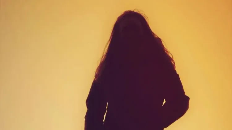 Silhouette of a long haired person on a light background
