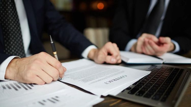 Business professionals review and discuss a contract document during a meeting.