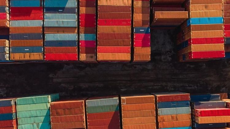 Stacks of colorful shipping containers are arranged in rows at a port.