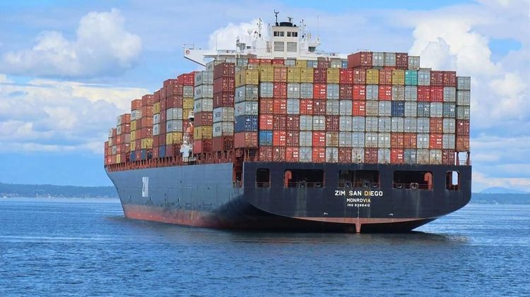 The container ship ZIM San Diego, loaded with colorful shipping containers, travels through Elliott Bay in Seattle, Washington.