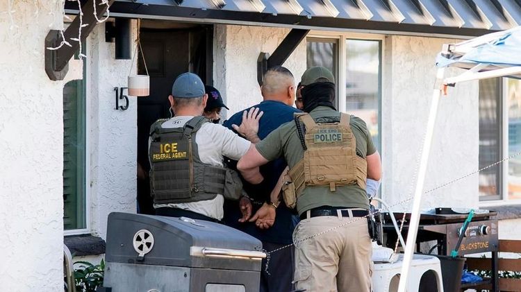 ICE Enforcement and Removal Operations officers and a federal agent detain a person at a home in Phoenix, Ariz.