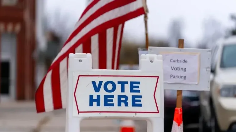 A “Vote Here” sign stands outside a polling place.