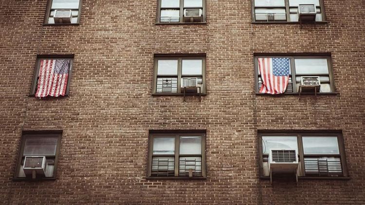 American flags hang from windows of a brick apartment building in Brooklyn, N.Y., during a presidential election.