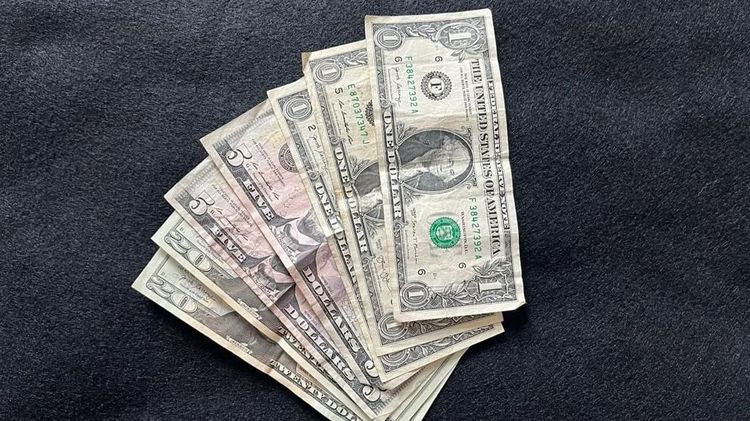 A collection of U.S. bills is displayed on a dark surface. Photo: Alan Wooten / The Center Square