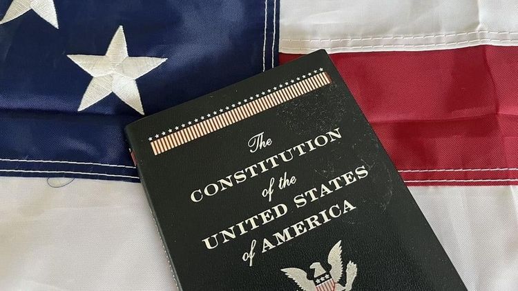 A pocket copy of the U.S. Constitution rests on an American flag. Photo: Alan Wooten / The Center Square
