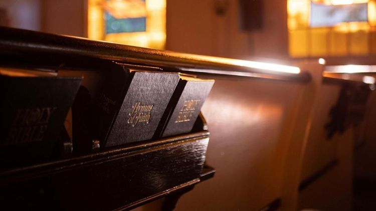 Bibles and hymnals rest in the back of a church pew.