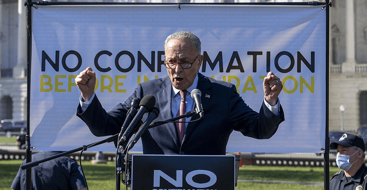 Chuck Schumer at a rally with fists raised.