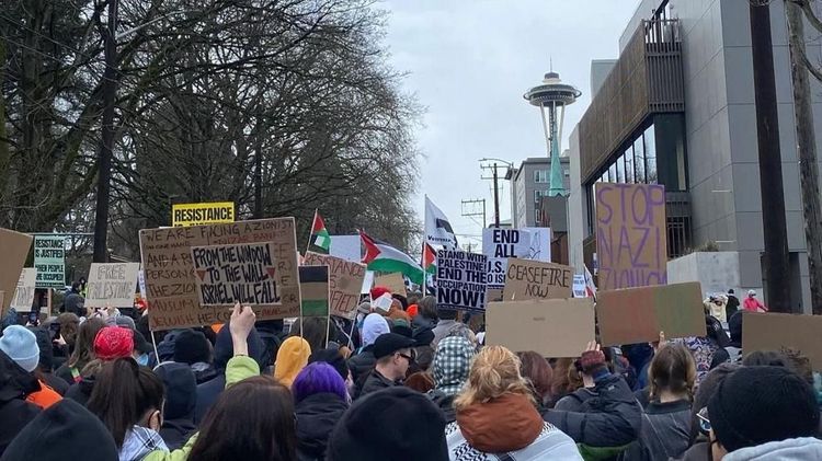 Protestors hold signs and flags while marching toward the Space Needle in Seattle.