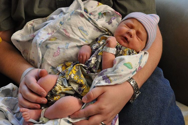 A man holds a newborn baby.