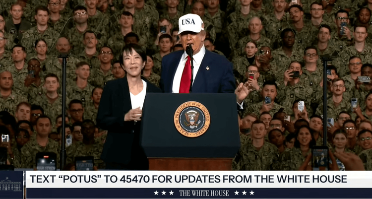 Newly elected Japan Prime Minister Sanae Takaichi joins President Trump on stage as he speaks to troops aboard the USS George Washington